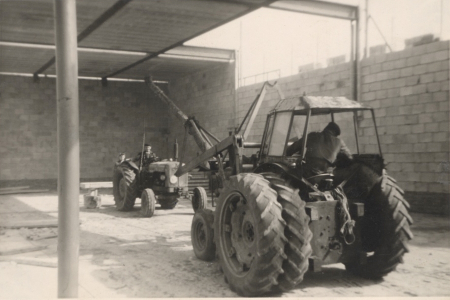 Een tractor met een zelfgebouwde giek van een boomstam, op de bouw van het zwembad in Wezep