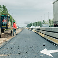 Wegverbreding in aanbouw met een nieuwe fundering en een wegwerker in oranje hesje