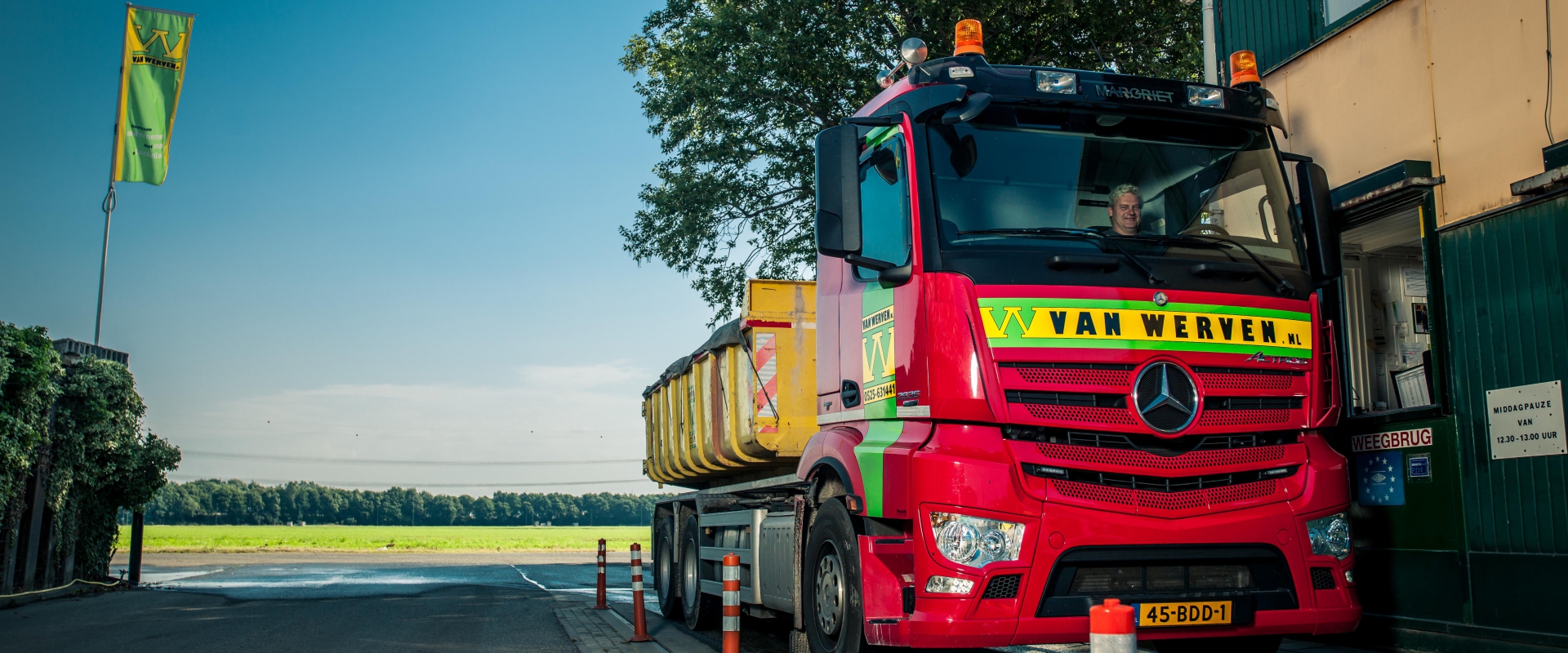 Vrachtwagen van Van Werven met gele container staat bij het loket van de weegbrug