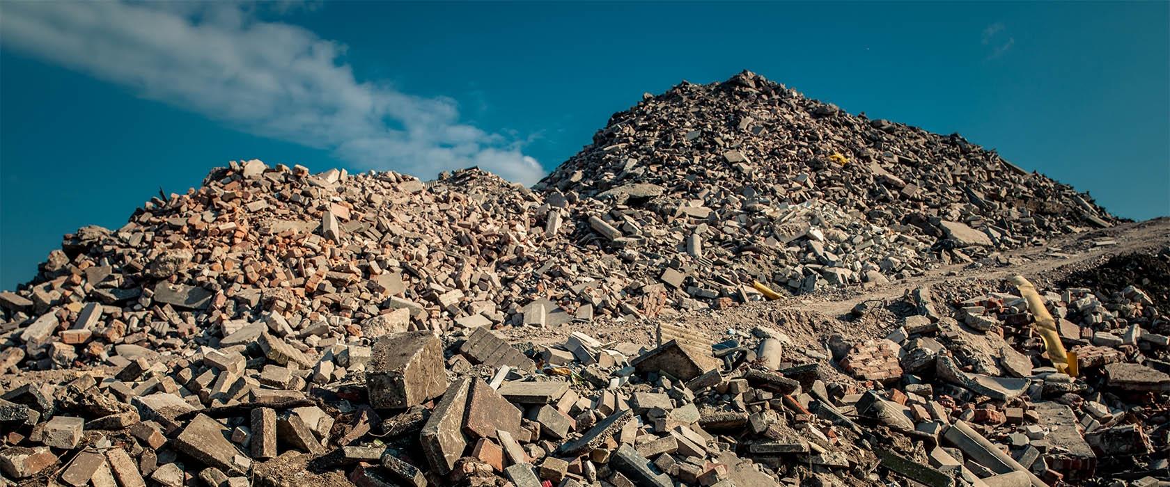 Twee hoge bergen gebroken metselwerk en beton op een recyclinglocatie onder een blauwe lucht